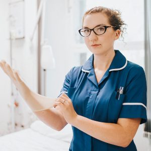 female-nurse-putting-on-a-glove-FVBFSHD.jpg